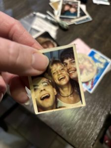 Eine Hand hält ein gedrucktes Foto von lachenden Menschen