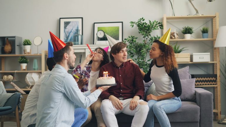 Freunde mit Partyhüten feiern Geburtstag mit Kuchen